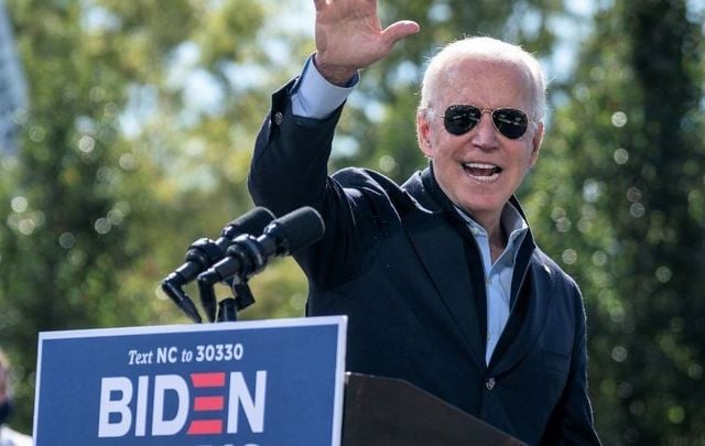 October 18, 2020: Joe Biden waves as he departs the stage during a drive-in campaign rally at Riverside High School in Durham, North Carolina. 