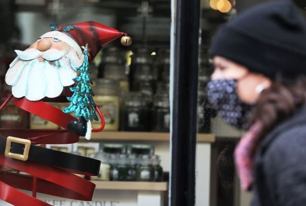 November 4, 2020: A person wearing a face mask passes a Christmas display in a shop window in St Stephen\'s Green shopping center.