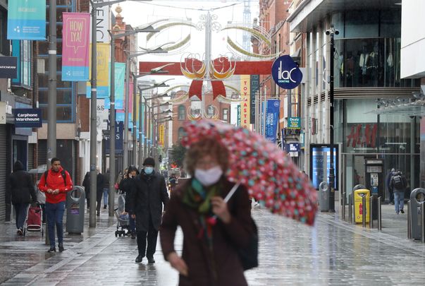 Christmas 2020: A woman wearing a mask to protect herself and others against COVID walks down Henry Street.