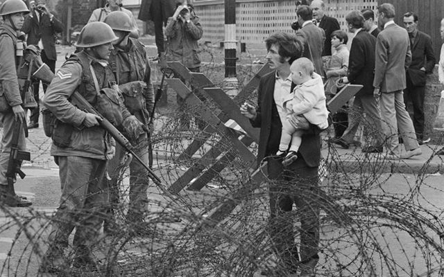 Aug 16, 1969: A civilian with his children confronts soldiers in the streets of Northern Ireland. 