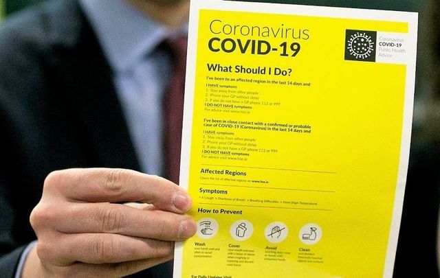 Minister for Health Simon Harris holds up a coronavirus fact sheet.
