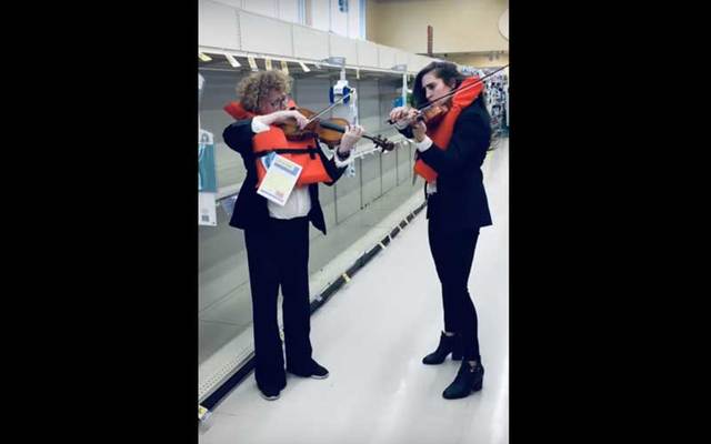 Violinists Emer Kinsella and Bonnie von Duyke play \"Nearer My Got To Thee\" in the empty toilet paper aisle.