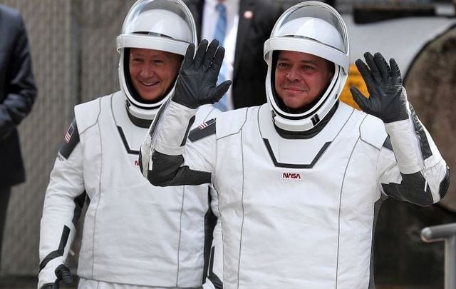 NASA astronauts Bob Behnken (R) and Doug Hurley (L) walk out of the Operations and Checkout Building on their way to the SpaceX Falcon 9 rocket with the Crew Dragon spacecraft on launch pad 39A at the Kennedy Space Center on May 27, 2020, in Cape Canaveral, Florida. 