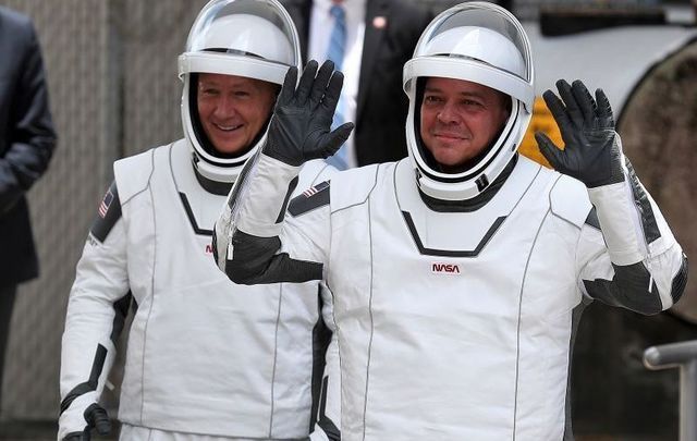 NASA astronauts Bob Behnken (R) and Doug Hurley (L) walk out of the Operations and Checkout Building on their way to the SpaceX Falcon 9 rocket with the Crew Dragon spacecraft on launch pad 39A at the Kennedy Space Center on May 27, 2020, in Cape Canaveral, Florida.