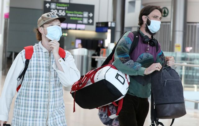 Passengers wearing masks walk through Dublin Airport.