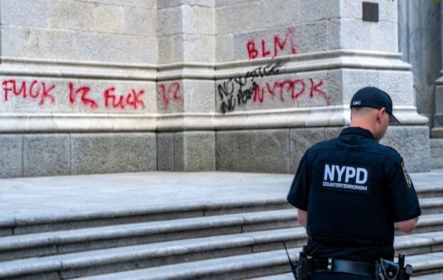 May 30, 2020: An NYPD officer walks by a vandalized St. Patrick\'s Cathedral in New York City. 