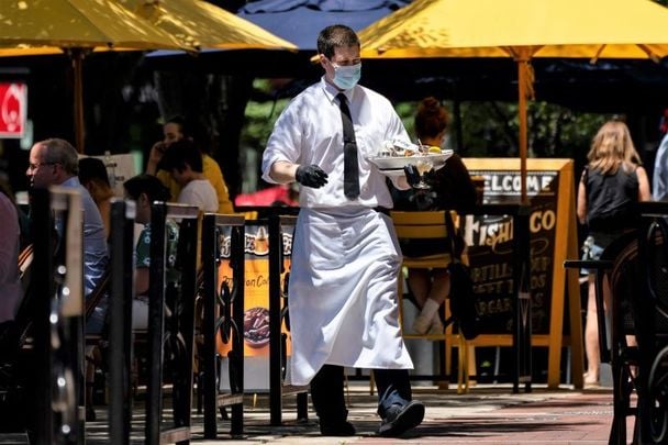 A waiter wearing a mask and gloves adjusts to the new normal as coronavirus restrictions ease.