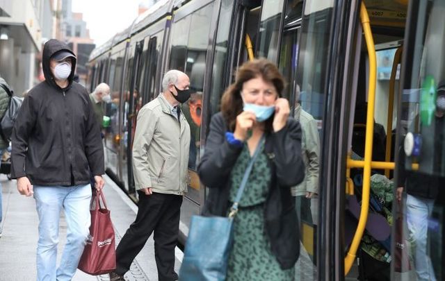 People wearing masks as they board and disembark the Luas in Dublin\'s City Center on July 4, 2020.
