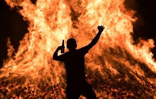 A young loyalist man is seen dancing at the Ballycraigy estate 11th night bonfire on July 11, 2020 in Antrim, Northern Ireland.