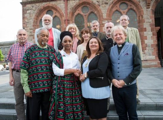 Panelists, organizers, & supporters of the \"Battle of the Bogside: 50 Years On\" event pose with former Derry mayor Michaela Boyle outside of Derry\'s Guildhall in August 2019.