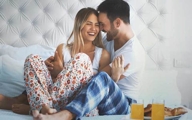 Couple shares breakfast in bed in luxury hotel. 