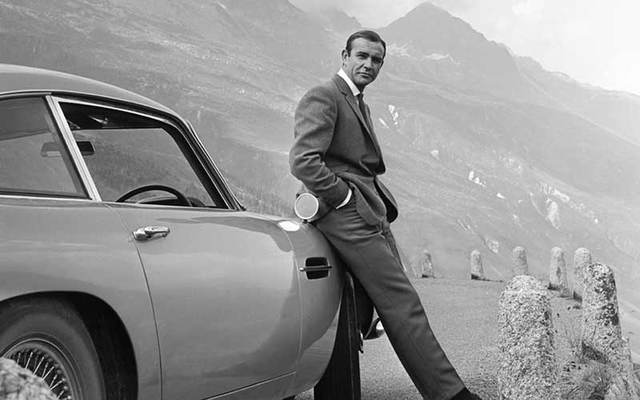 Sean Connery as James Bond posing next to his Aston Martin DB5 in a scene from 1964’s “Goldfinger.”