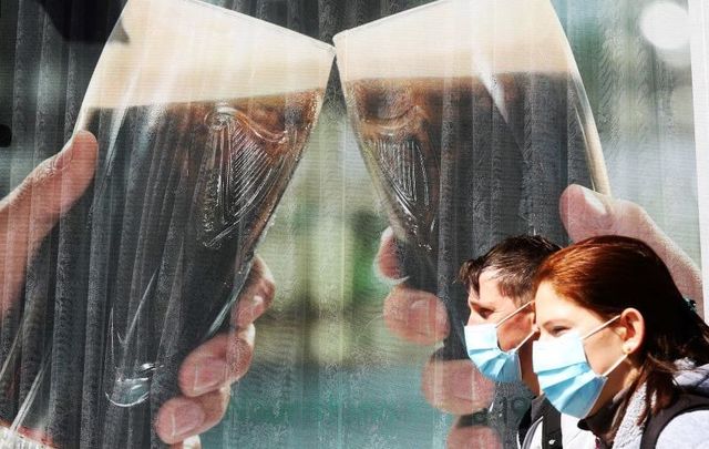 May 11, 2020: People wearing masks pass a pub in Dublin City. Ireland\'s \"wet\" pubs have been closed since March.