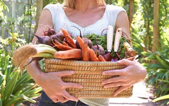 A woman holding a basket of vegetables.