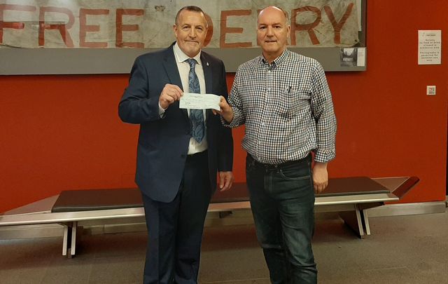 Malachy McAllister presents a check to Tony Doherty at the Museum of Free Derry.
