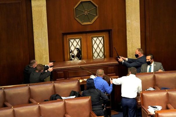 January 6, 2021: Law enforcement officers point their guns at a door that was vandalized in the House Chamber during a joint session of Congress in Washington, DC.