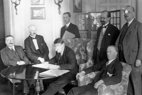 December 6, 1921: Members of the Irish delegation at the signing of the Irish Free State Treaty between Great Britain and Ireland, London, England. The delegation includes seated from left, Sinn Fein founder Arthur Griffith, Eamon Duggan, Irish Minister for Finance Michael Collins, and politician Robert Barton. Standing from left are author Robert Erskine Childers, lawyer George Gavan Duffy, and John Chartres.