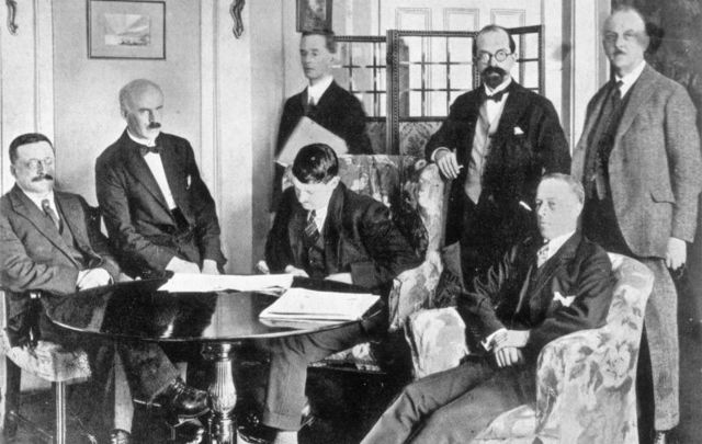 December 6, 1921: Members of the Irish delegation at the signing of the Irish Free State Treaty between Great Britain and Ireland in London, England. The delegation includes seated from left, Sinn Fein founder Arthur Griffith, E.J. Duggan, Irish Minister for Finance Michael Collins, and politician Robert Barton. Standing from left are author Robert Erskine Childers, lawyer George Gavan Duffy, and John Chartres.