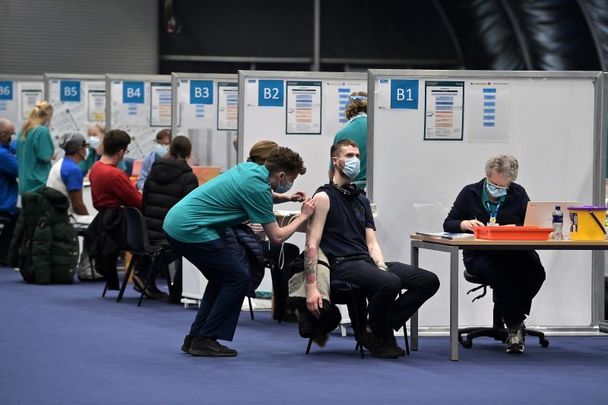 December 21, 2021: A member of the medical staff at the Titanic Exhibition Centre which has been transformed into a vaccination centre vaccinates one of the first members of the public to arrive as the mass vaccination centre opens in Belfast, Northern Ireland. 