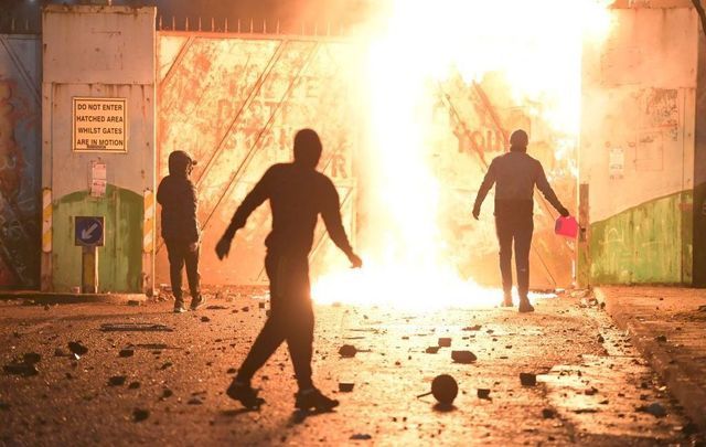 Loyalist rioters burn a gate in a peace wall in Belfast. 