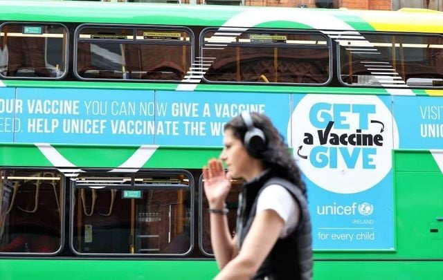July 2, 2021: A person passing by a Dublin Bus which bears an advertisement for vaccines.