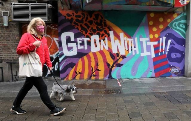 August 2020: A person wearing a face mask passes a mural that reads \'Get On With It\' in Dublin.