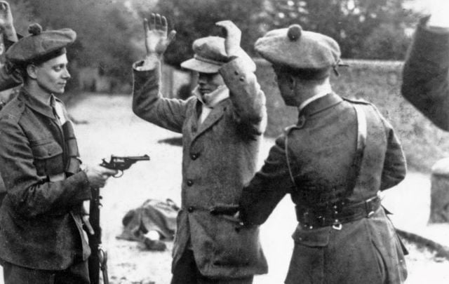 A suspected member of the Irish nationalist party Sinn Fein is searched at gunpoint by temporary constables of the British Black and Tans, during the Irish War of Independence, Ireland, November 1920. 