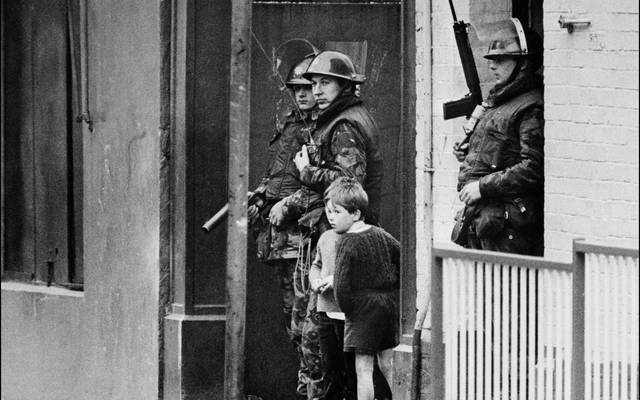 Children stand next to British soldiers during The Troubles in Northern Ireland.
