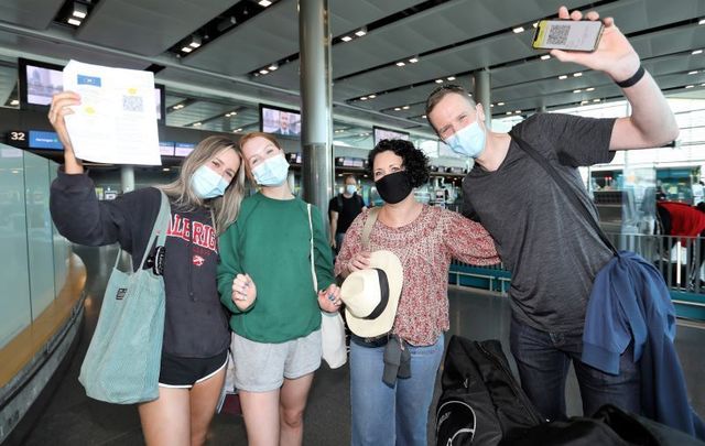 July 19, 2021: Travelers at Dublin AIrport wearing face masks and holding their Covid Vaccine certs on the day that international travel returns for Ireland.