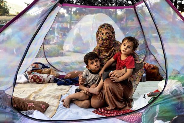 August 12, 2021: Farzia, 28, who lost her husband in Baghlan one week ago to fighting by the Taliban sits with her children, Subhan, 5, and Ismael, 2, in a tent at a makeshift IDP camp in Share-e-Naw park to various mosques and schools in Kabul, Afghanistan. 