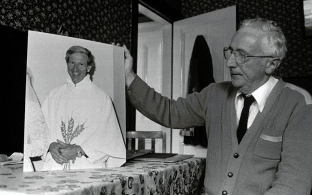 Fr. Niall Molloy\'s brother Billy poses beside his photograph during a campaign for justice in 1986. 
