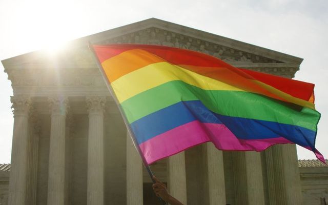 An LGBTQ+ supporter waves a rainbow flag at the United States Supreme Court on the morning of the landmark Obergefell decision legalizing gay marriage nationwide.