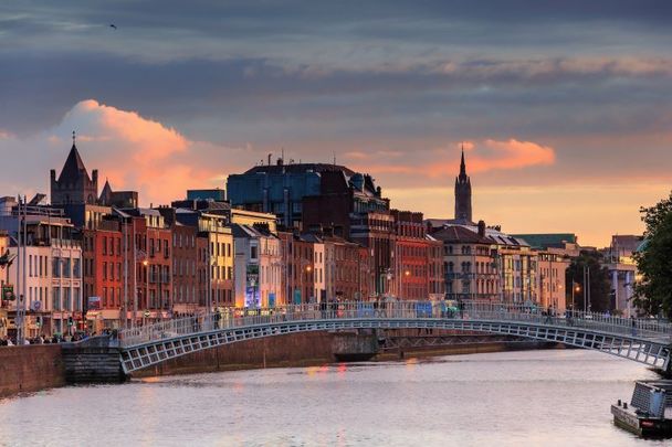 People walking on the Ha\'Penny Bridge at sunset in Dublin, Ireland