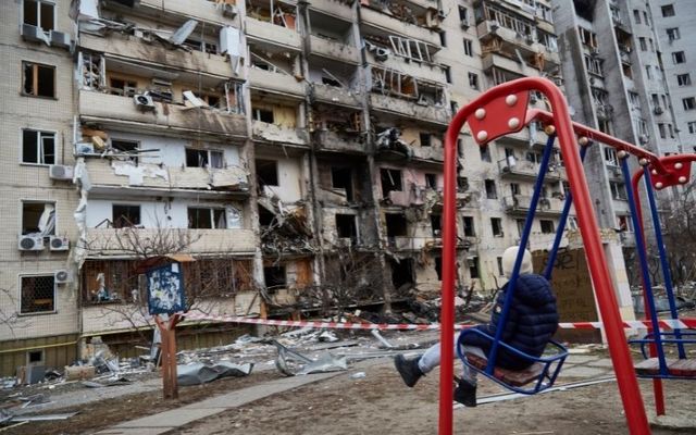  A child on a swing outside a residential building damaged by a missile on February 25, 2022, in Kyiv, Ukraine.