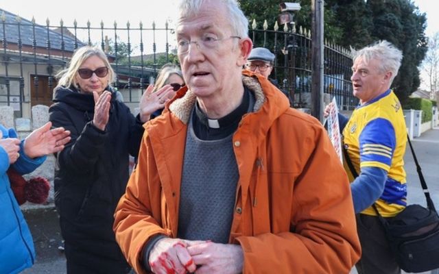 Fr. Fergal MacDonagh with red paint on his hands outside the Russian Embassy in Dublin. 