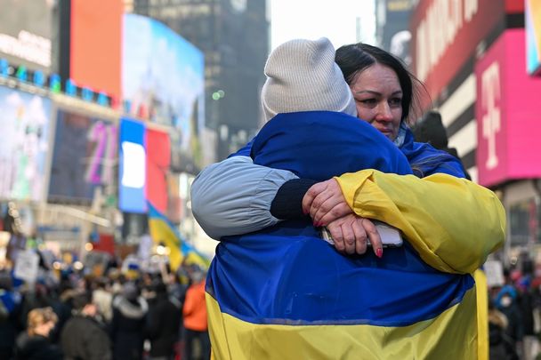 Two people hug, draped in Ukrainian flags, at the \"Stand with Ukraine\" rally at Times Square, on Feb 26, 2022.