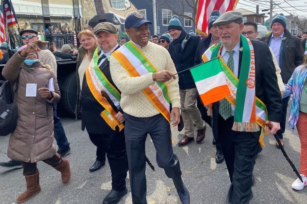 New York City Mayor Eric Adams waves a Tricolor in the Rockaways; alongside him are the parade’s grand marshal John Samuelsen and chairman Mike Benn.
