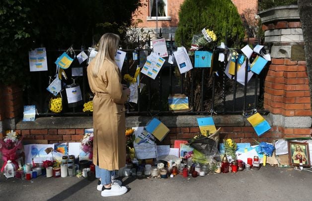 Svitlana Kopyl looking at flowers and cards hanging the rails supporting the people of Ukraine in their war against the Russian invasion outside the Ukraine embassy in Dublin