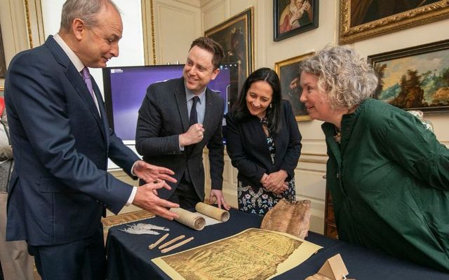 Taoiseach Micheál Martin (left) examines recovered documents from the Public Record Office with Dr. Peter Crooks, Minister for Culture Catherine Martin, and Trinity Provost Dr. Linda Doyle. 
