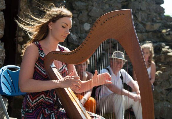 A harpist playing the harp at Dunluce Castle, County Antrim.