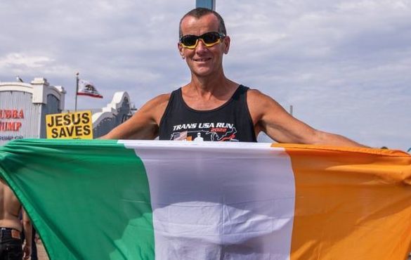 Richard Donovan holds the Irish flag at Santa Monica Pier after finishing a 3,200-mile run across the US. 