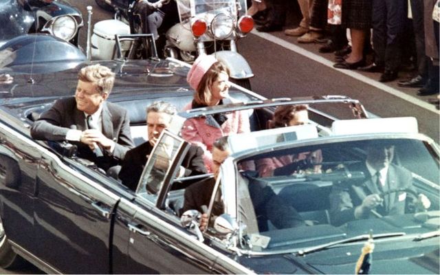 November 22, 1963: President Kennedy in the limousine driven by William Greer in Dallas, Texas, on Main Street, minutes before the assassination. Also in the presidential limousine are Jackie Kennedy, Texas Governor John Connally, and his wife, Nellie.