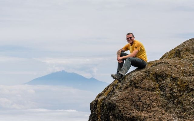Kalebh Fynes perched on the edge of a cliff 4,000 metres above sea level, at Karanga Camp on Mount Kilimanjaro