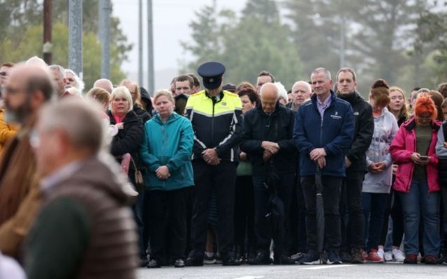 A lone Garda with people as they pay their repects at the memorial on honour of those that died in the Creeslough explosion a year ago.
