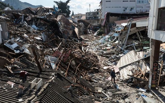 A man walks past collapsed buildings on February 08, 2023, in Hatay, Turkey. 