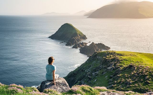 A woman gazing over the Devil Horns at Dunmore Head, Dingle Peninsula, Co Kerry.