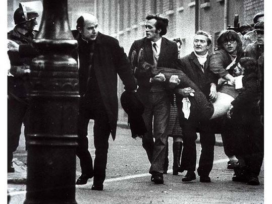 An iconic shot from Bloody Sunday of a wounded man being carried from the street by civil rights marchers. 