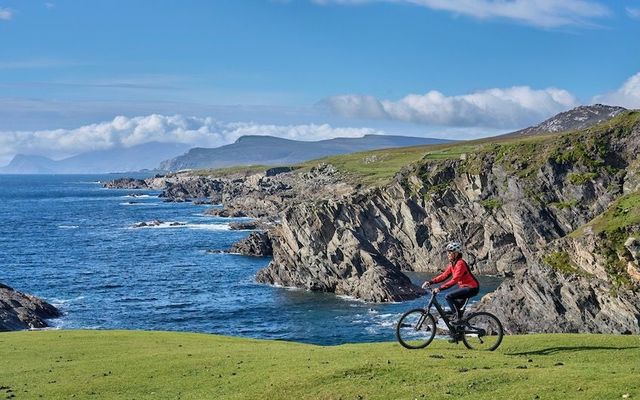 Woman cycling in the rough karst area of Burren near Ballyvaughan, County Clare in the western part of the Republic of Ireland.