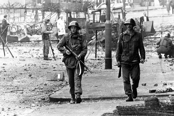 August 16, 1989:  British soldiers on patrol beside barbed wire defences at the junction of Percy Street and Falls Road in Belfast during unrest in Northern Ireland.