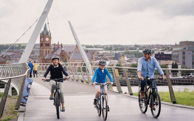 Family cycling over Peace Bridge, Derry.
